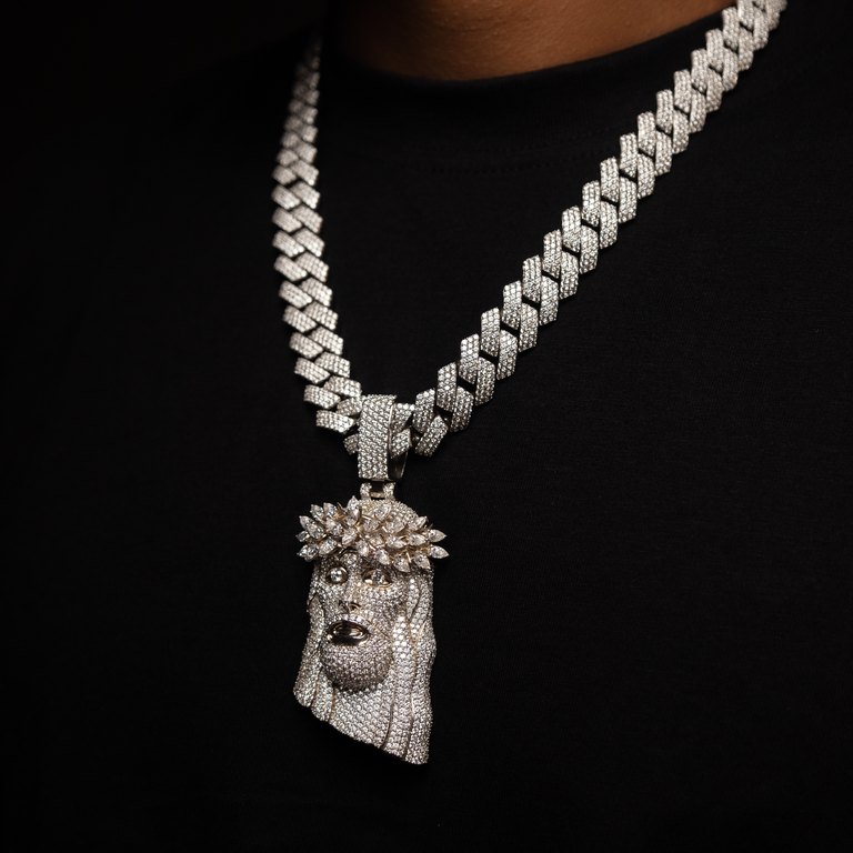 Diamond face pendant hanging from a diamond chain against black.