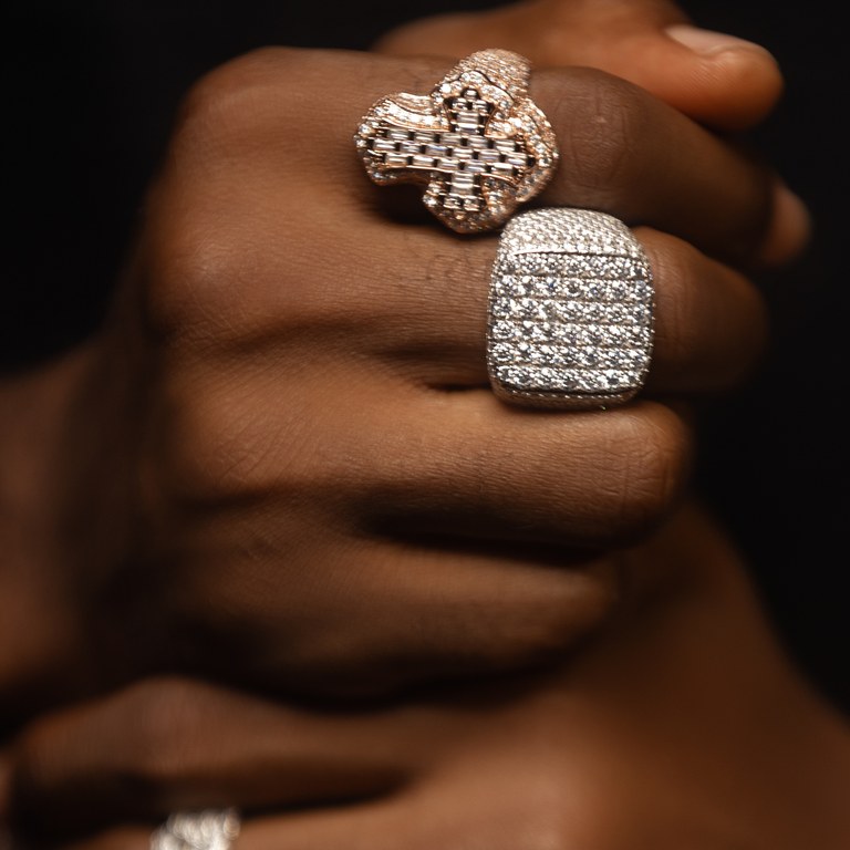 Two diamond-encrusted rings worn on a hand against black.