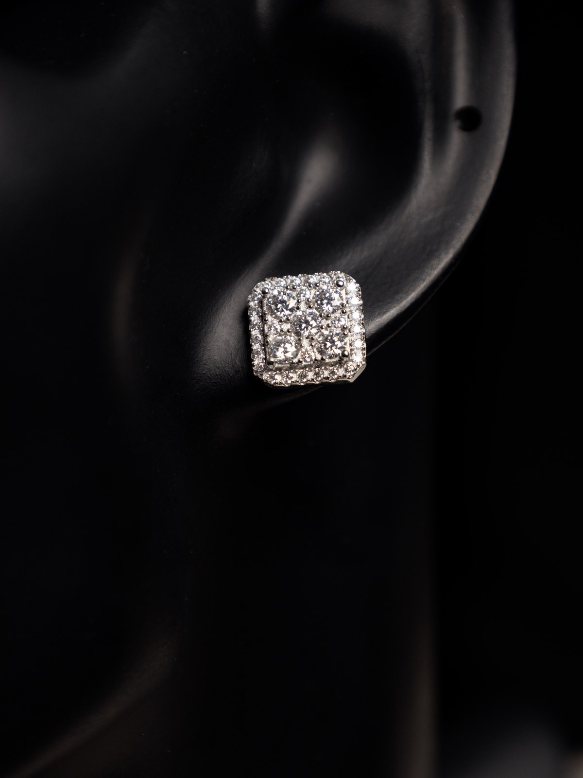 Diamond earring photographed on a black ear display.