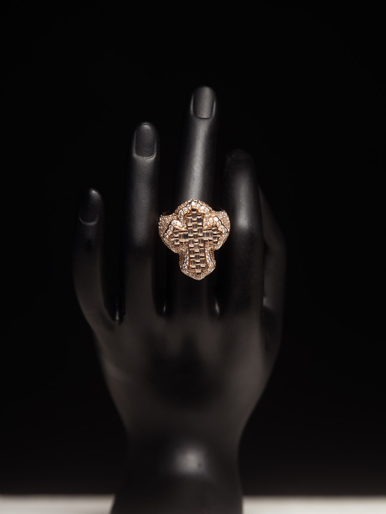 Diamond-encrusted ring displayed on a black hand form.
