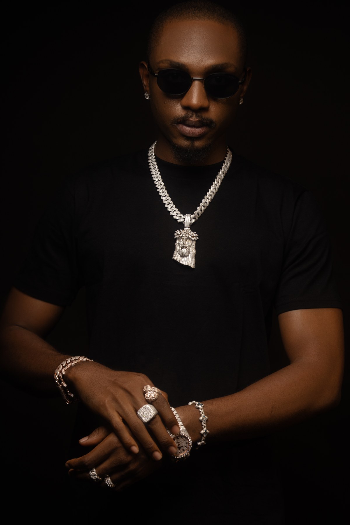 Man in sunglasses wearing layered diamond chains and a pendant.