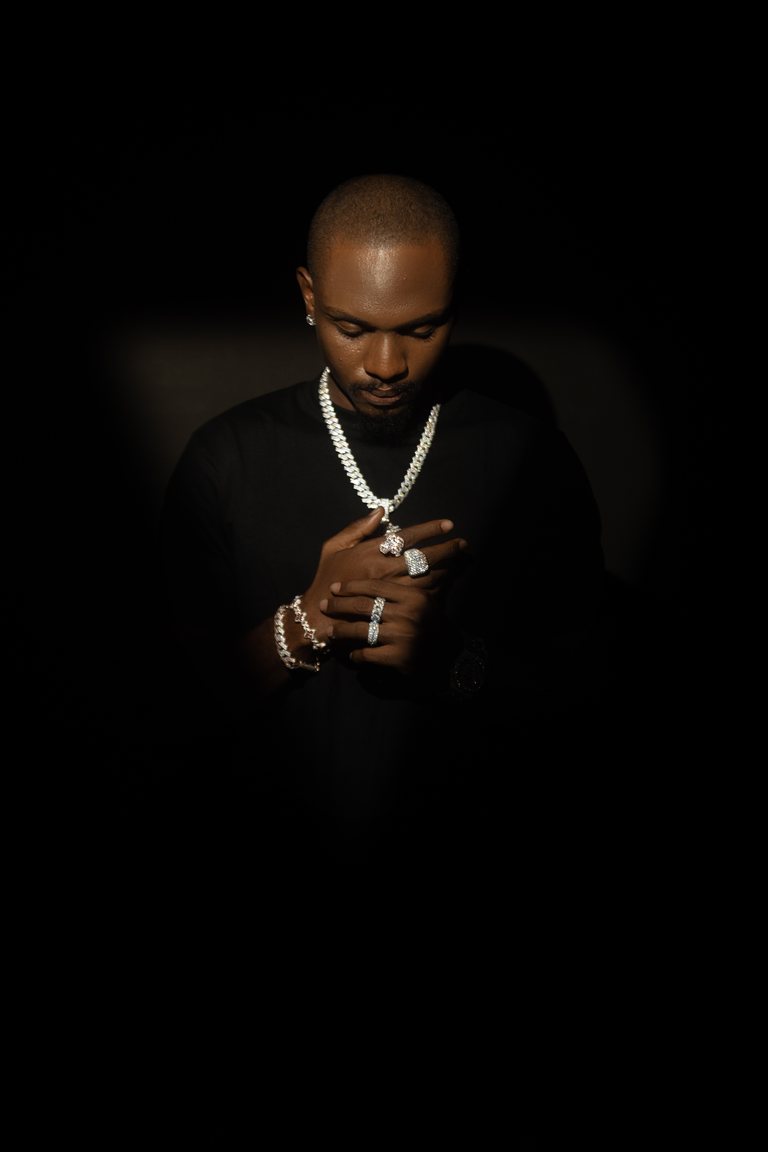 Editorial portrait of a model wearing layered jewelry against a dark background