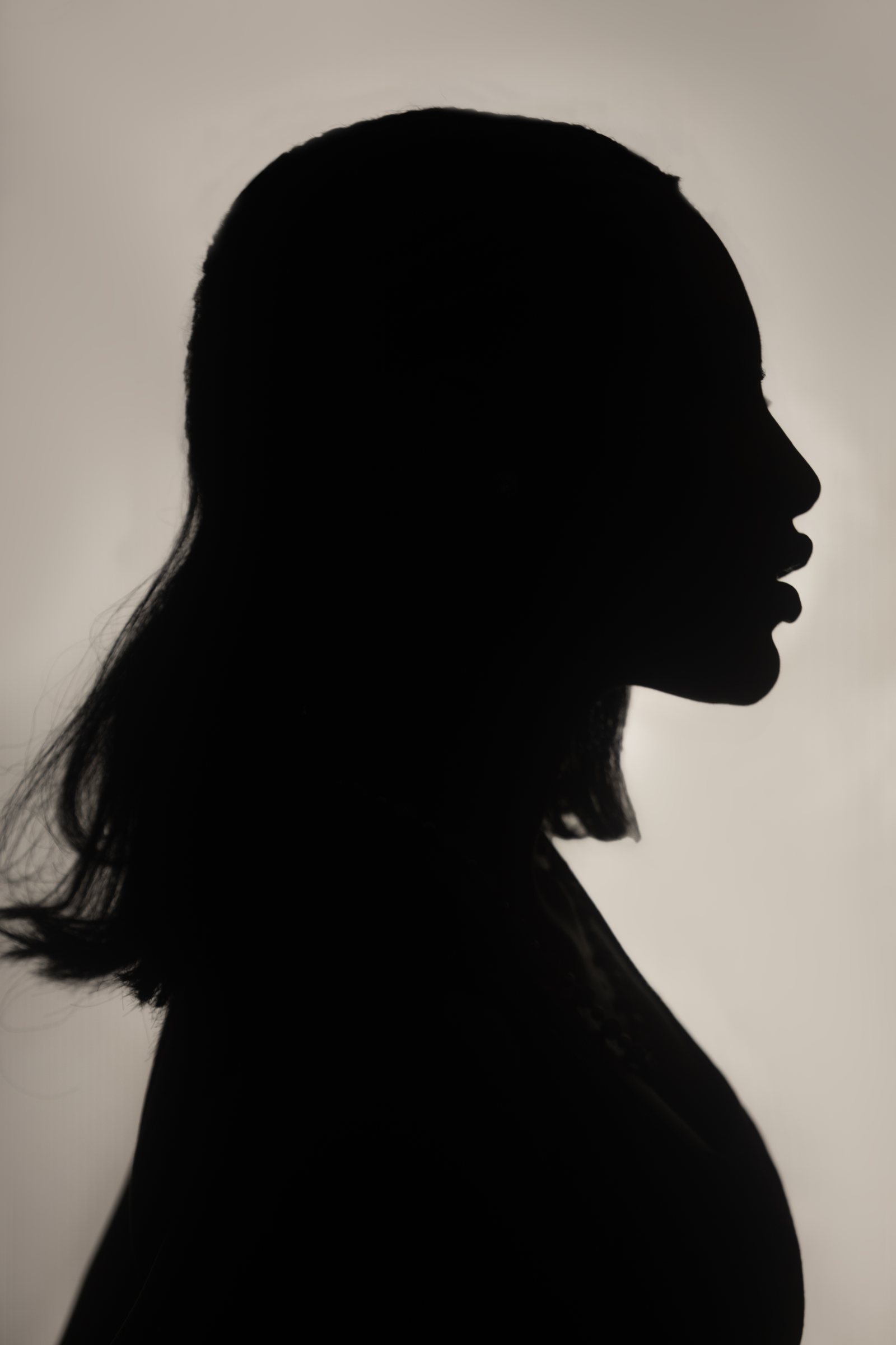 Side-profile silhouette of a woman against a warm light background.